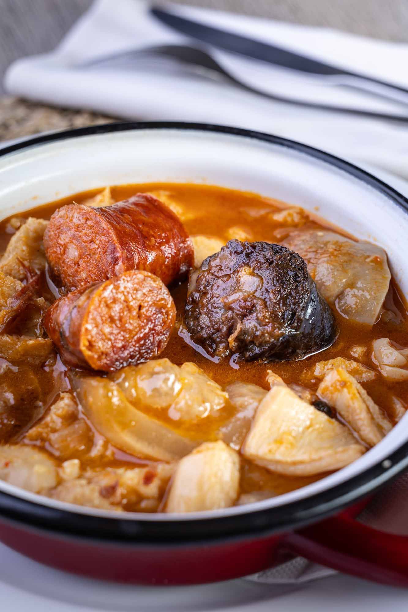 Un primer plano de un tazón de sopa con carne y verduras sobre una mesa.