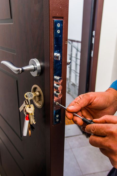 Una persona está arreglando una cerradura de puerta con un destornillador.