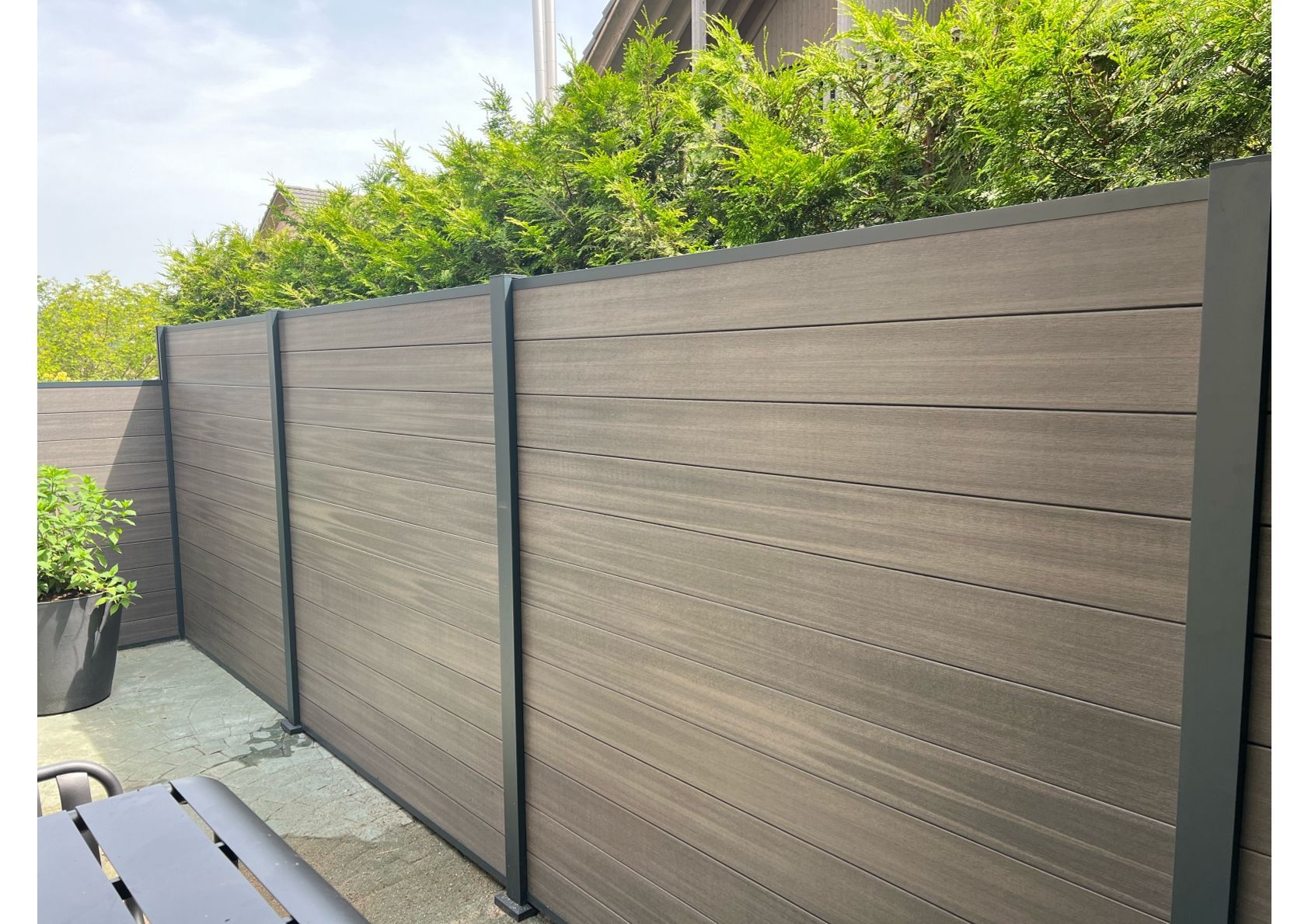 Brauner Holzzaun mit dunklen Metallpfosten im Außenbereich.