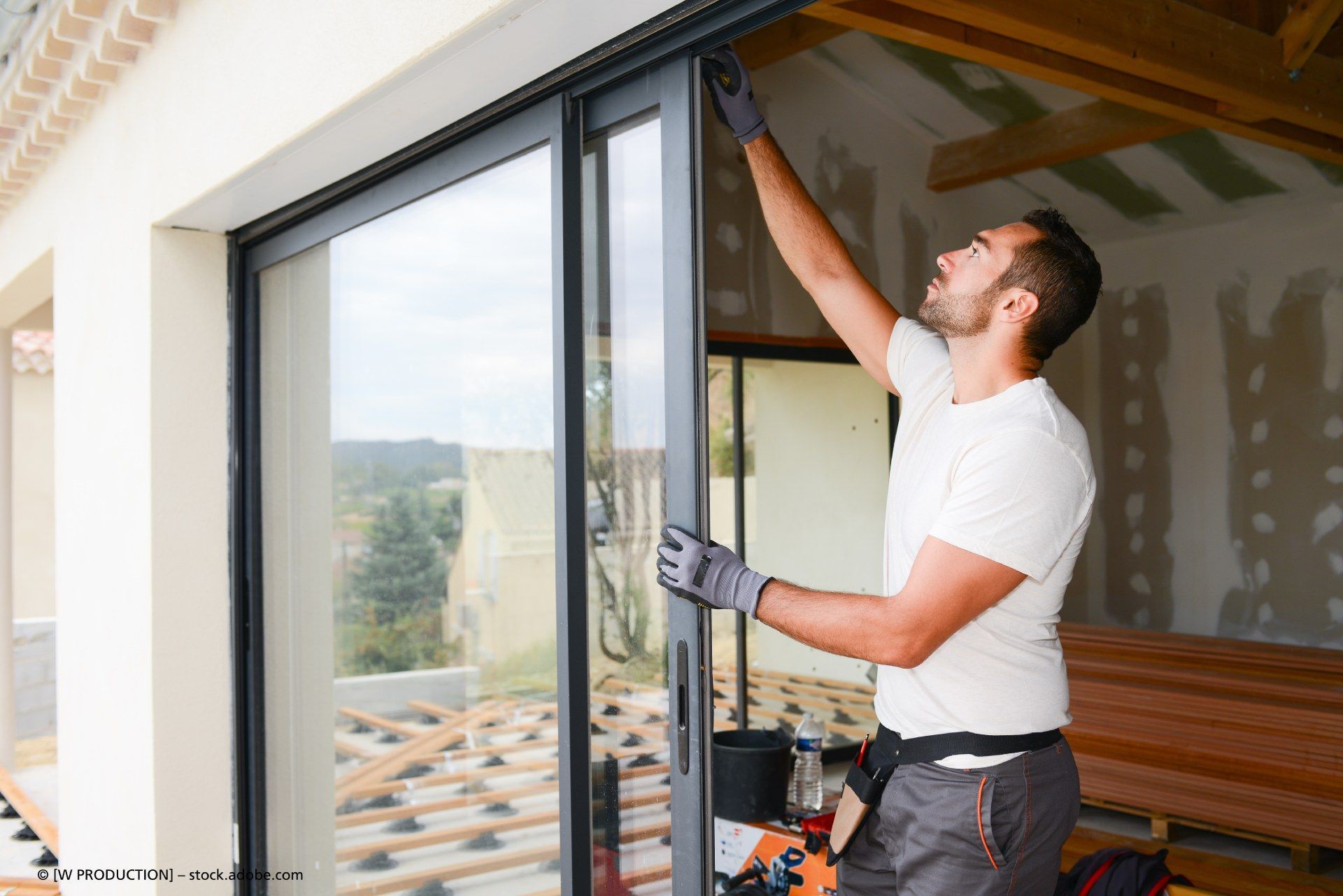 Handwerker prüft Funktion von Glasschiebetür