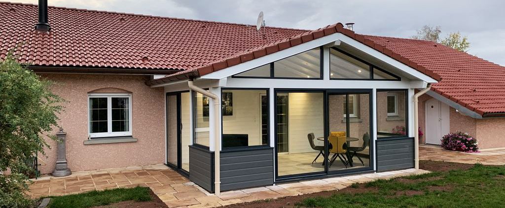 Maison de plain-pied avec une véranda vitrée et un toit en tuiles rouges