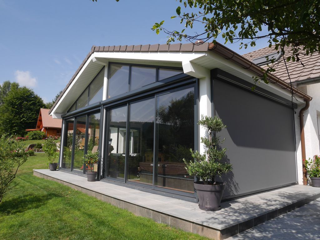 Maison moderne avec un toit en pente et une grande baie vitrée donnant sur une cour gazonnée