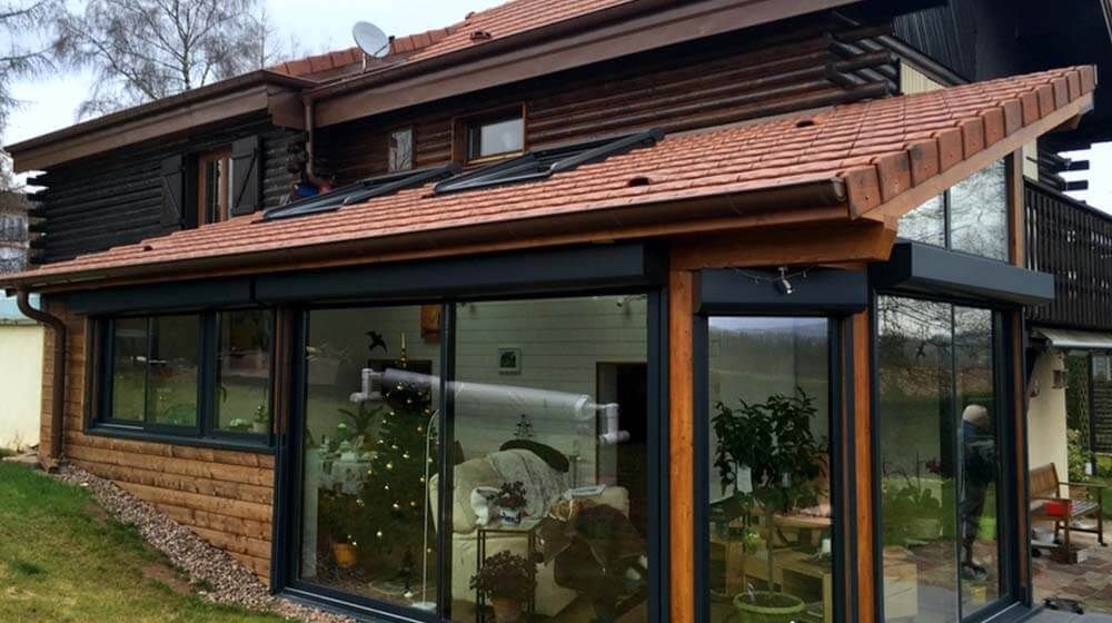 Extérieur de maison moderne avec un toit de tuiles brunes et de grandes fenêtres vitrées