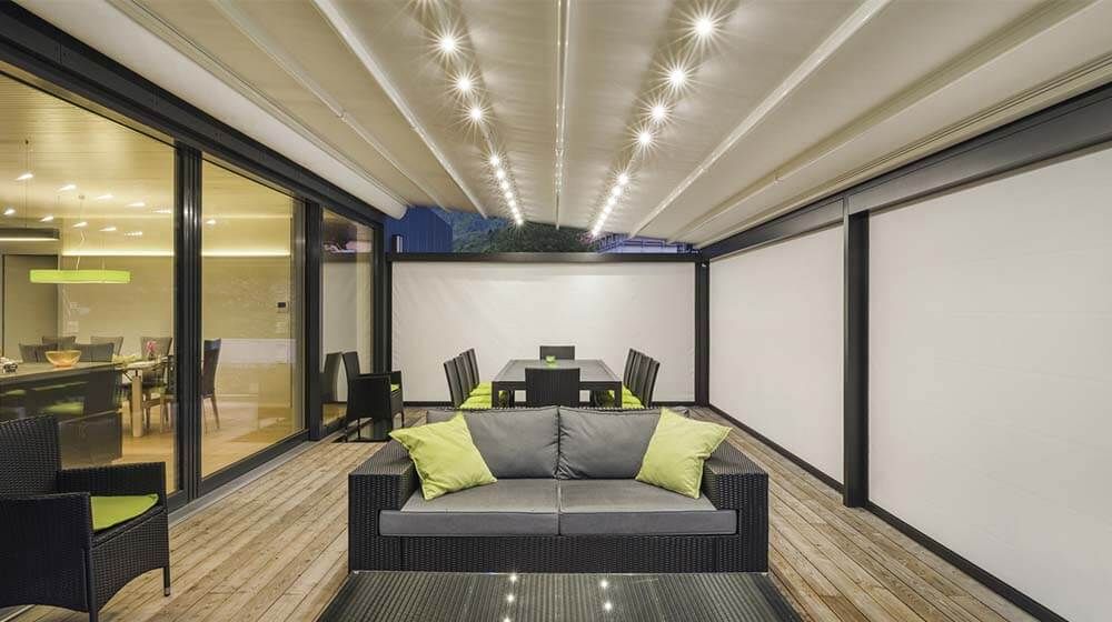 Salon intérieur moderne avec canapé gris, coussins vert citron et table à manger dans une élégante pièce aux parois de verre