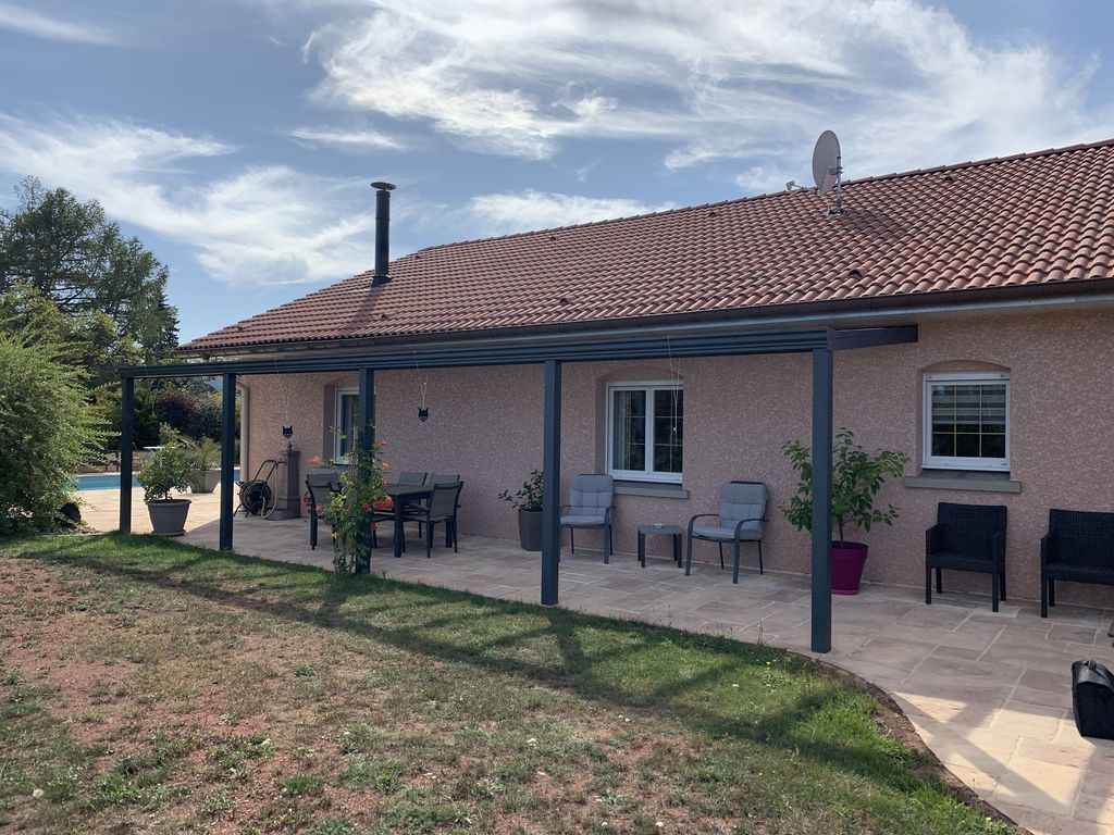 Maison de plain-pied avec toit de tuiles rouges, terrasse couverte et chaises d'extérieur dans un jardin ensoleillé
