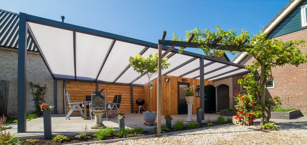 Patio moderne avec pergola, sièges d'extérieur, plantes en pot et une maison en briques sous un ciel bleu