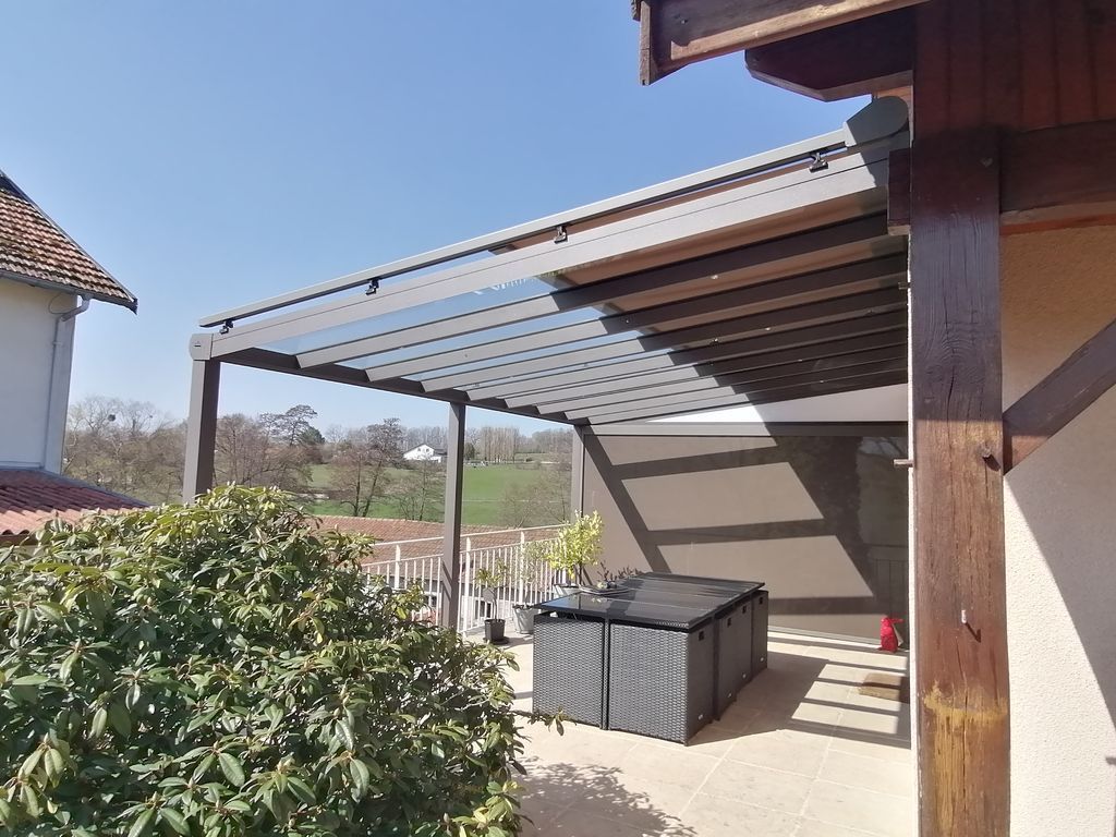 Terrasse couverte avec pergola, canapé d'extérieur et vue sur la colline par une journée ensoleillée