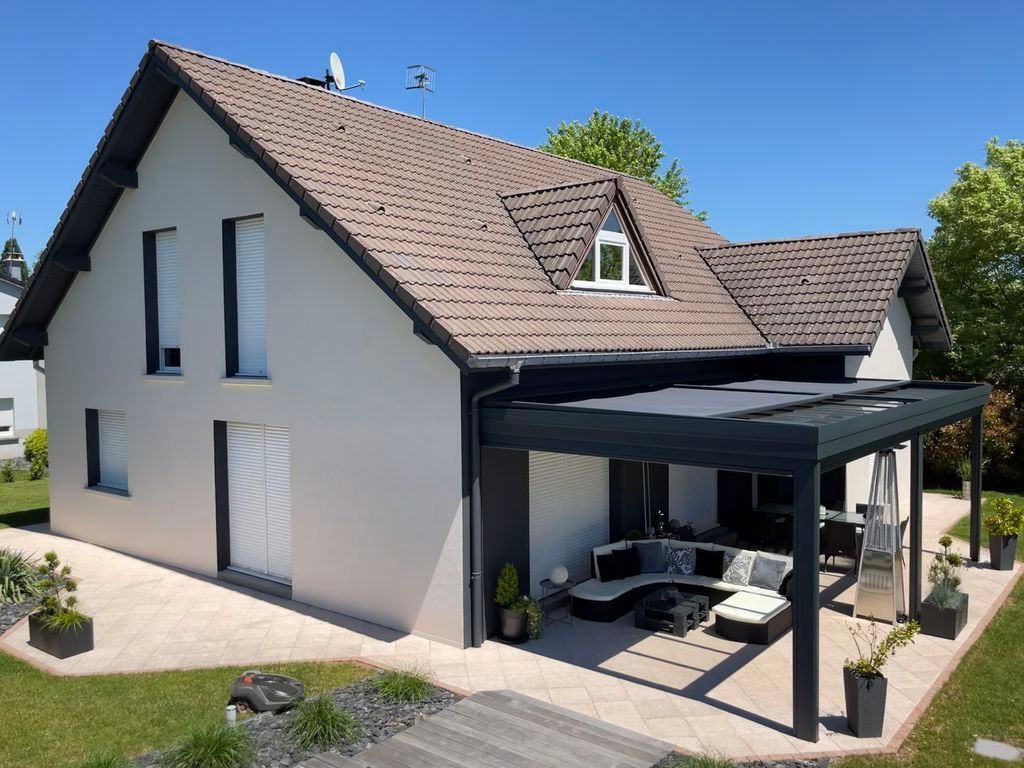 Maison moderne à deux étages avec un toit sombre et une terrasse couverte par une journée ensoleillée