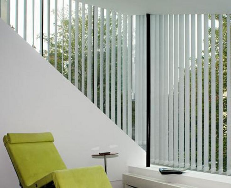 Pièce moderne avec fauteuil vert citron, mur blanc et stores verticaux hauts près de la fenêtre