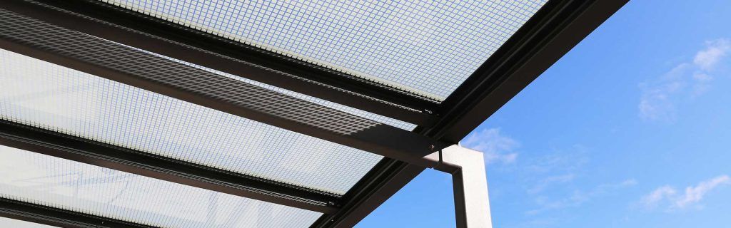 Toiture de terrasse en tôle ondulée se détachant sur un ciel bleu, vue d'en bas