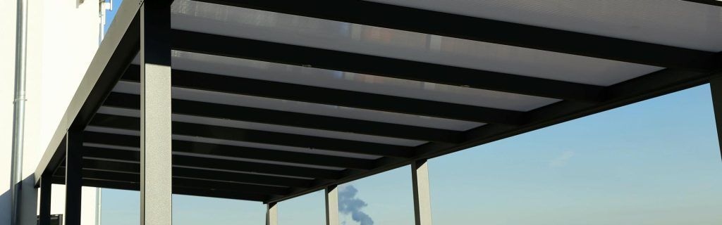 Pergola moderne aux poutres sombres donnant sur un ciel d'un bleu éclatant