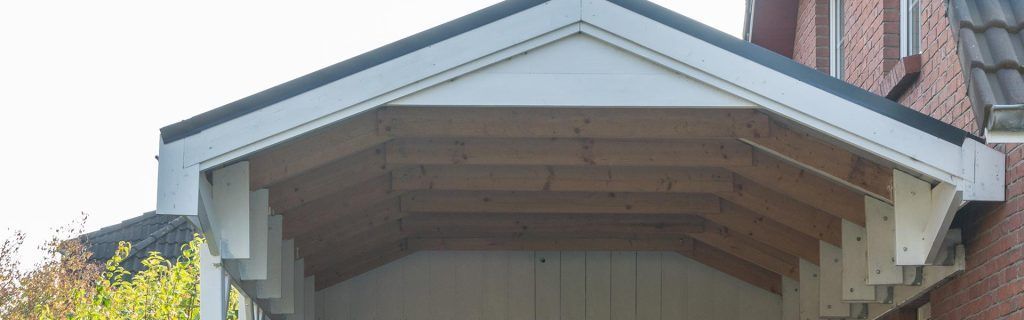 Porche couvert avec boiseries blanches et plafond voûté en bois sur une maison en briques