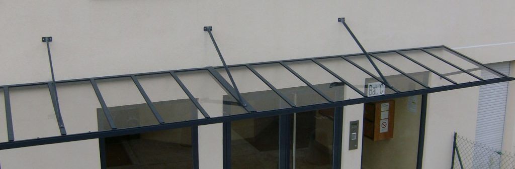 Auvent métallique avec barres de support au-dessus de l'entrée et des fenêtres d'un bâtiment