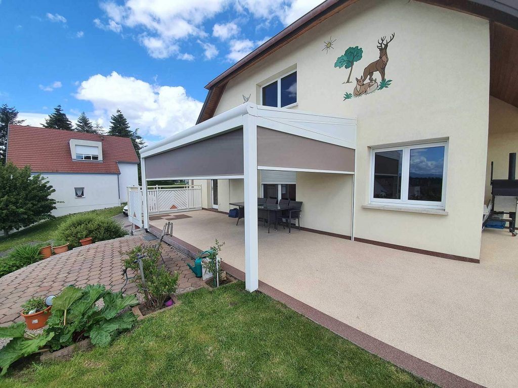 Extérieur de la maison avec patio couvert, jardin et pelouse par une journée ensoleillée