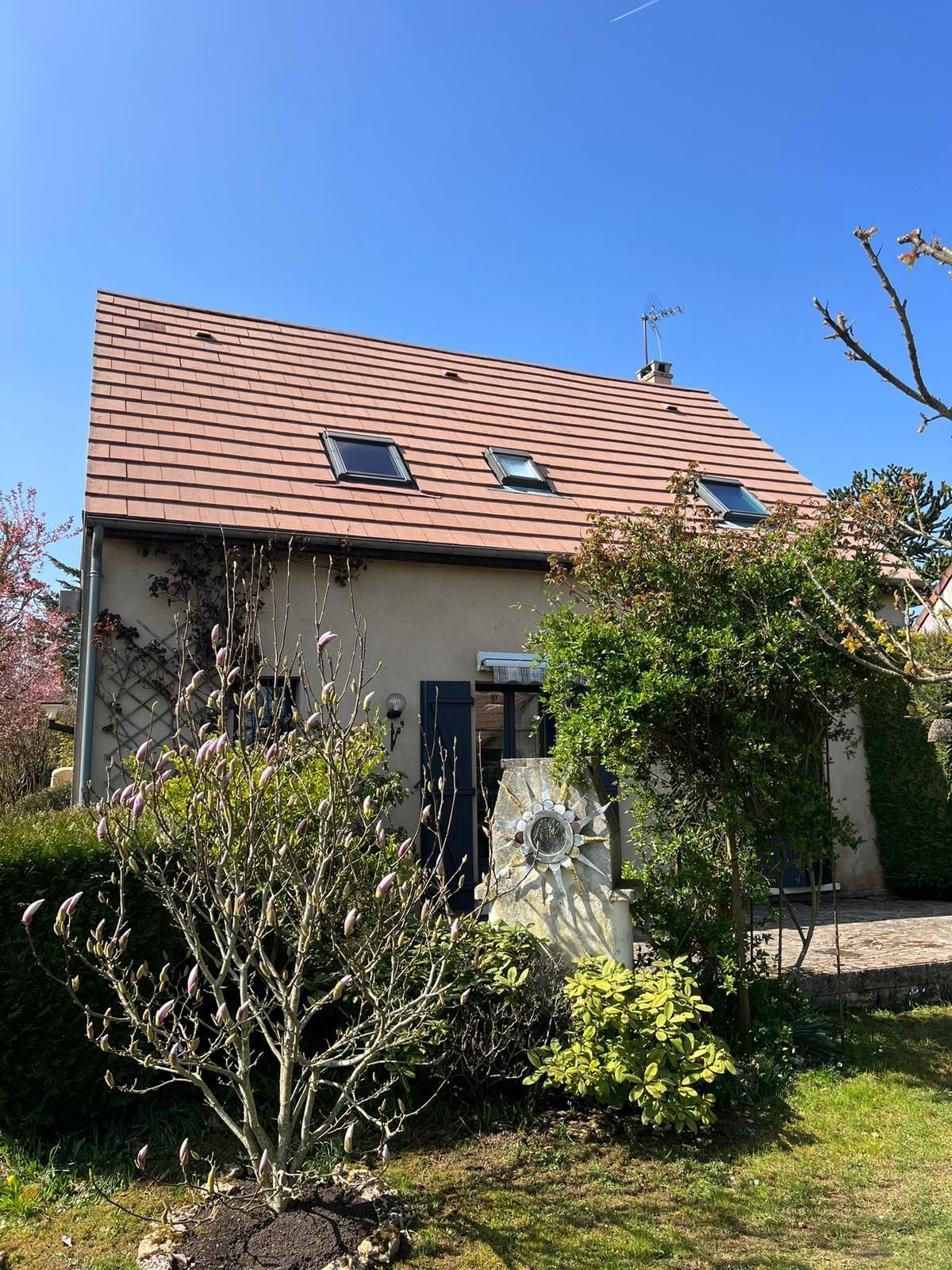 Deux ouvriers en gilets orange recouvrent un toit endommagé d'une bâche bleue pendant la pluie.