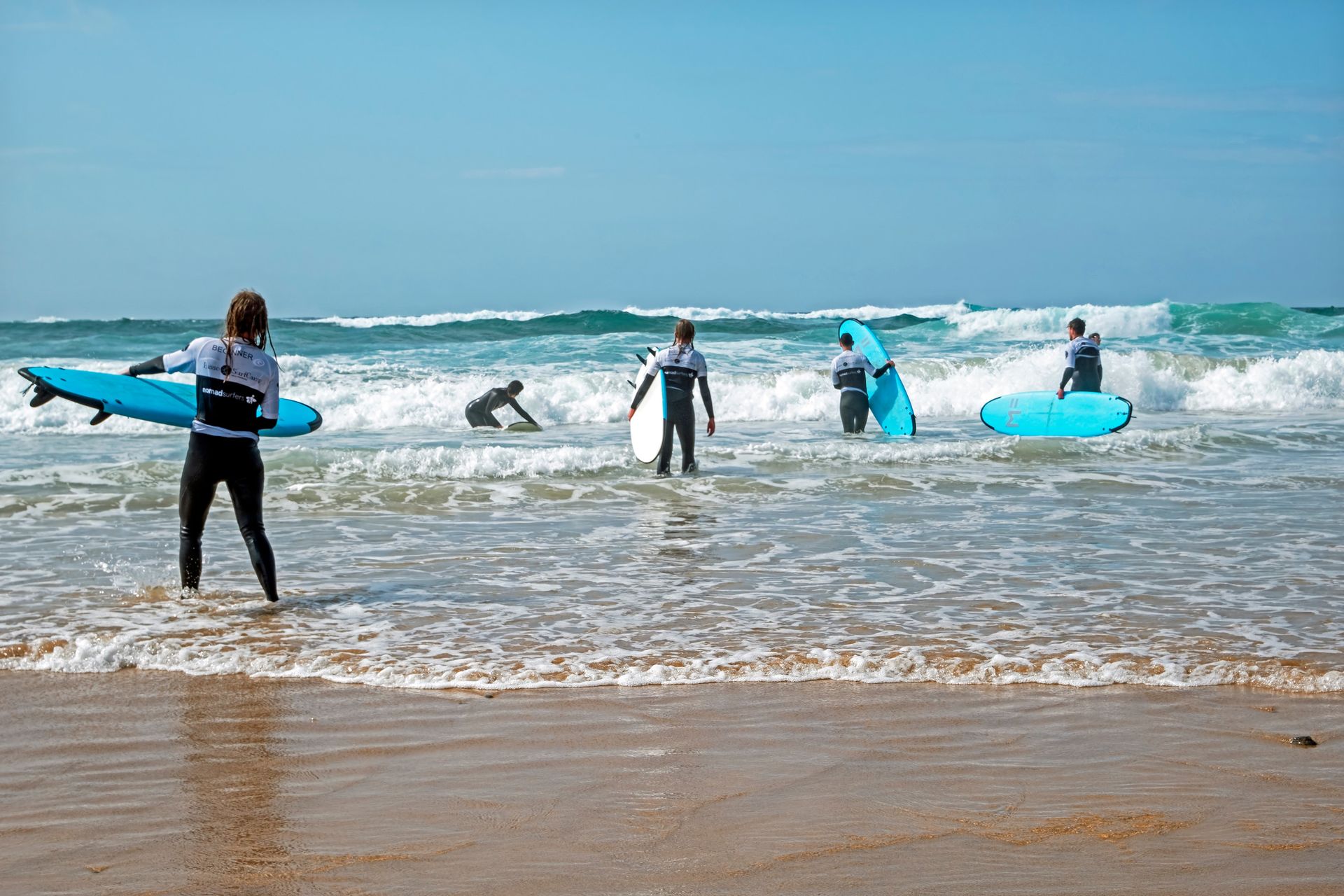 Un grupo de personas están de pie en una playa sosteniendo tablas de surf.