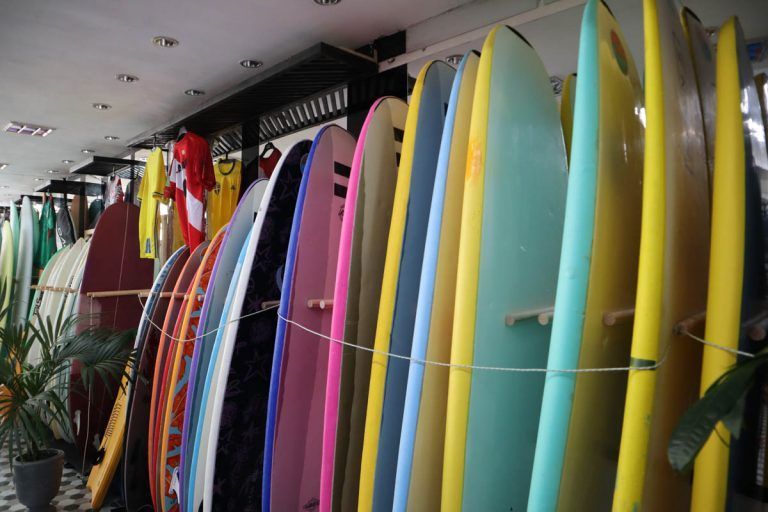Un montón de tablas de surf están colgadas en la pared de una tienda.