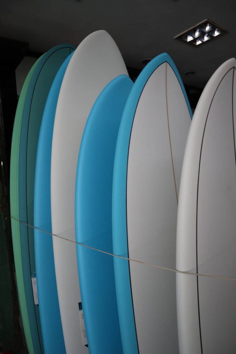 Un montón de tablas de surf están alineadas en fila