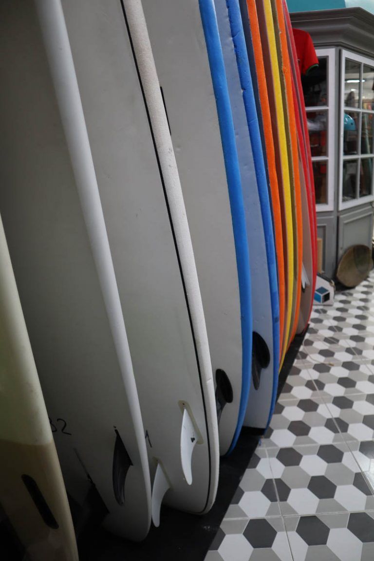 Una fila de tablas de surf están alineadas sobre un suelo de baldosas.