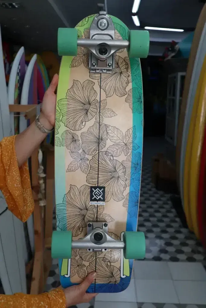 Una persona sostiene una patineta con un diseño floral.
