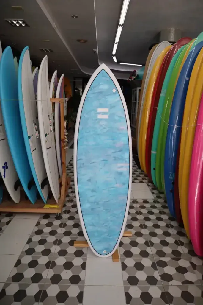 Una tabla de surf azul está delante de una fila de tablas de surf.