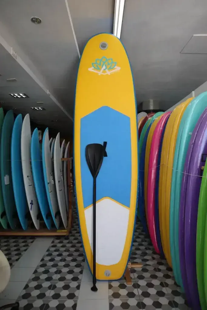 Una tabla de surf amarilla y azul con un remo en una tienda
