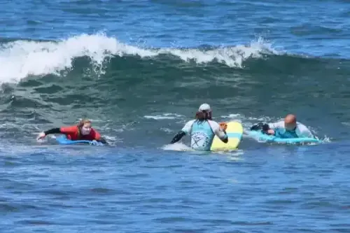 Tres personas están montando olas en tablas de surf en el océano.
