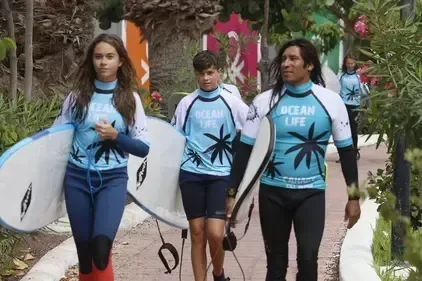 Un grupo de personas que llevan tablas de surf y llevan camisetas con motivos de la vida marina.