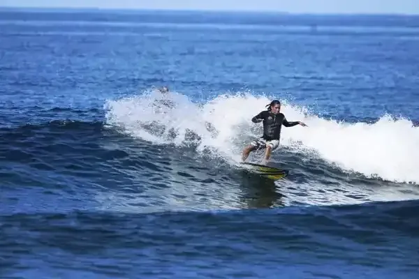 Un hombre está montando una ola en una tabla de surf en el océano.