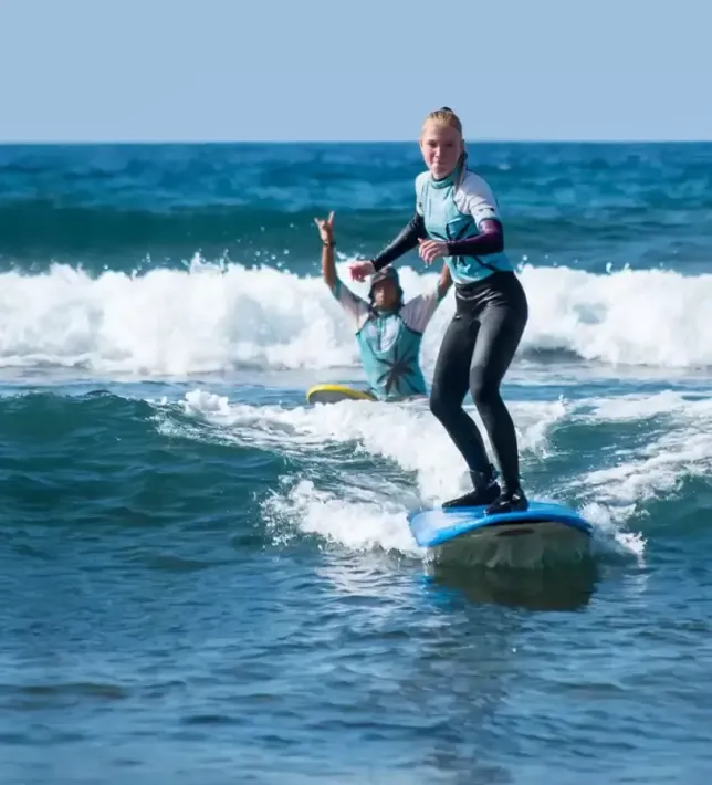 Una mujer está montando una ola en una tabla de surf en el océano.