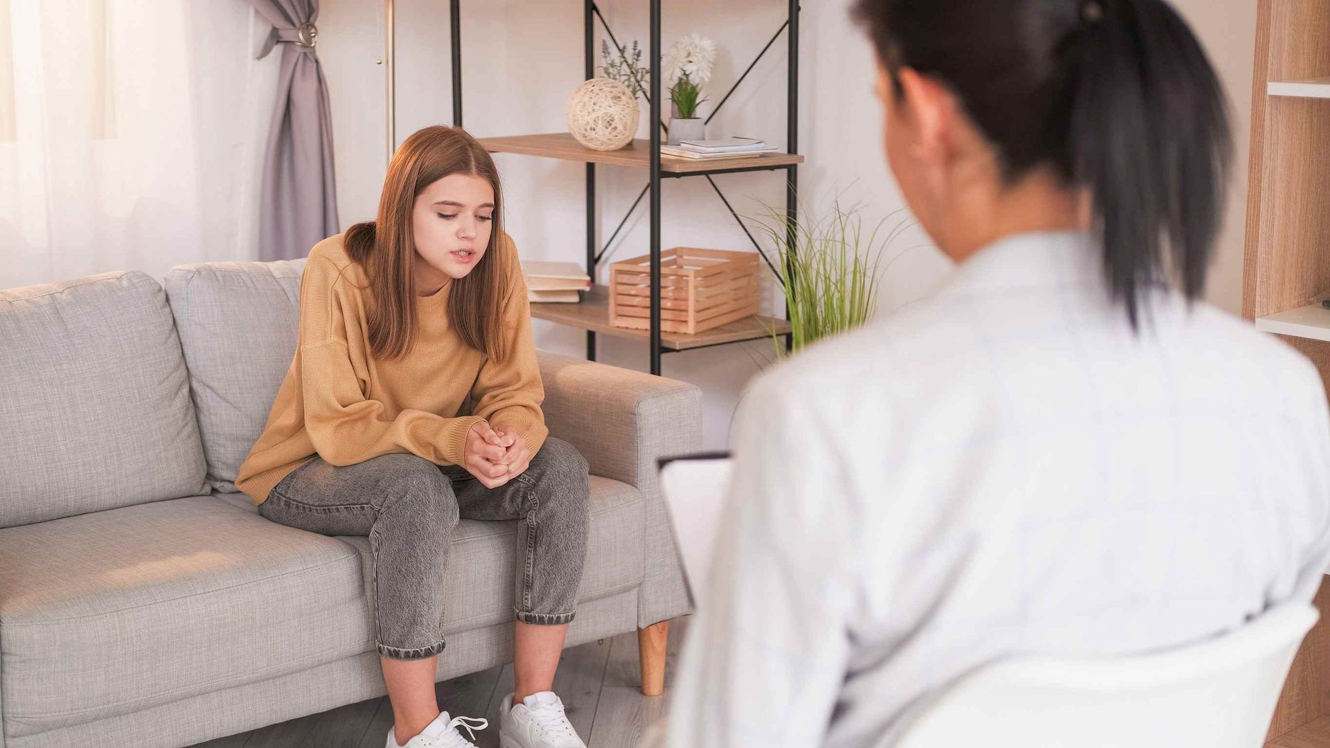 Una mujer está sentada en un sofá hablando con un terapeuta.