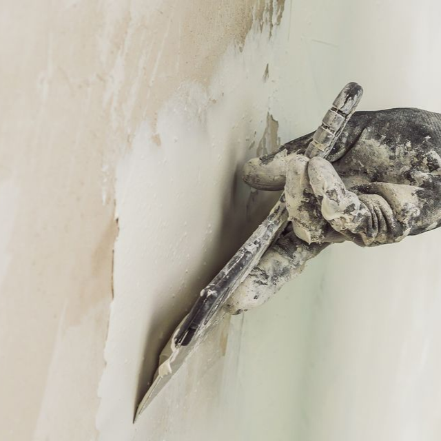 Gros plan sur le lissage manuel d'un enduit mural à la truelle.