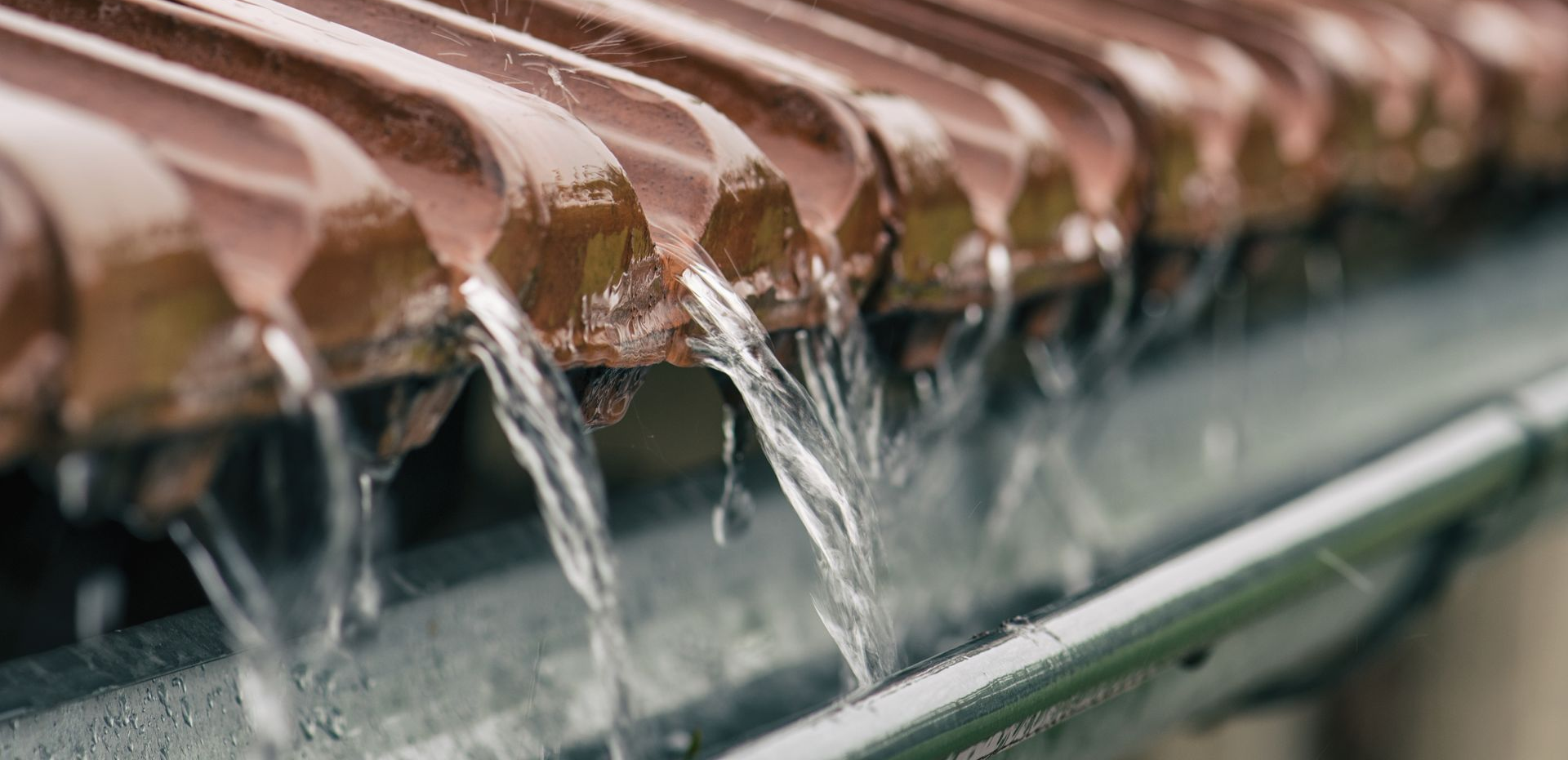 Eau de pluie ruisselant d'une gouttière en cuivre.