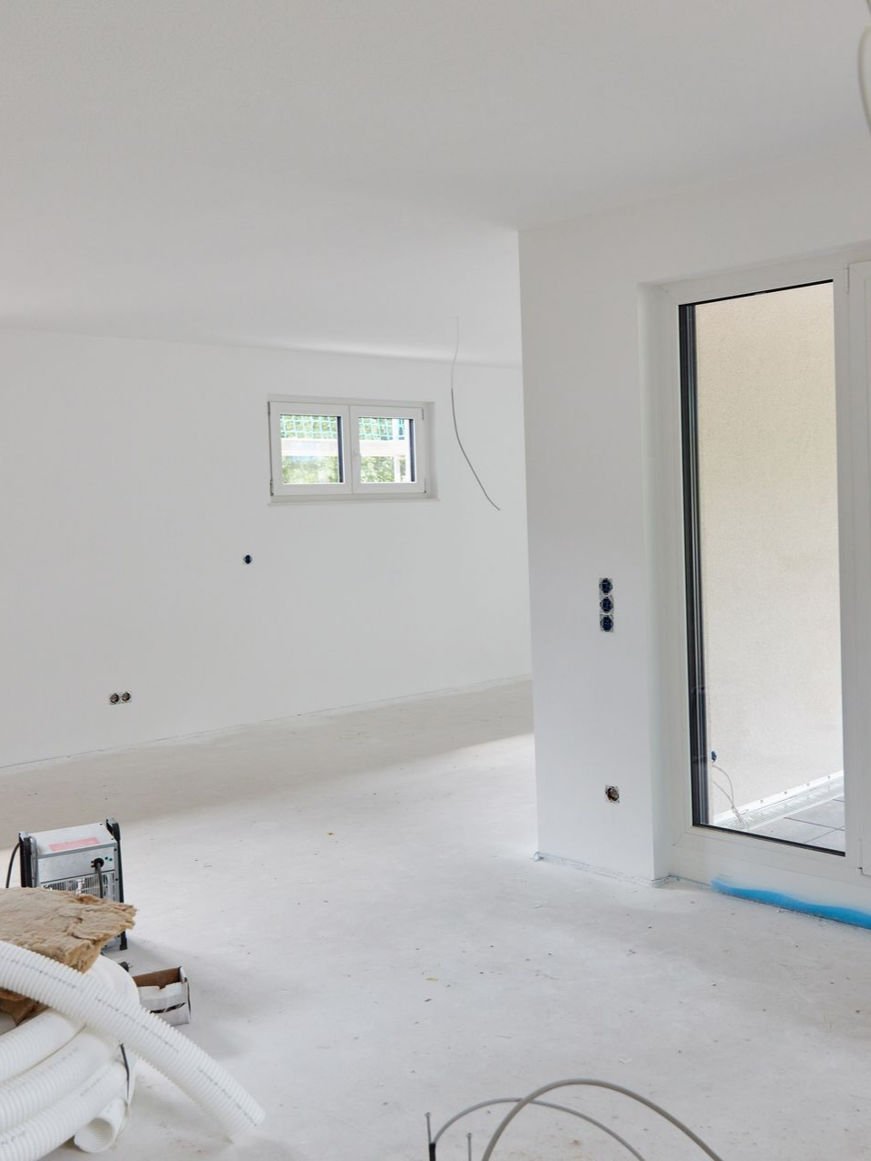 Vue intérieure d'une pièce en construction avec murs blancs.