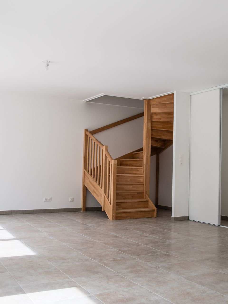 Escalier en bois dans une pièce lumineuse.