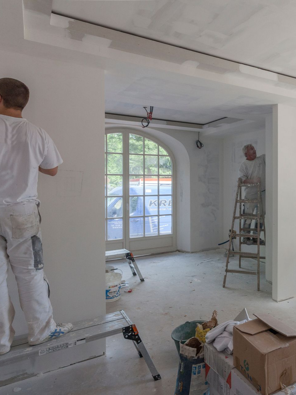 Deux personnes peignent les murs intérieurs d'une pièce.