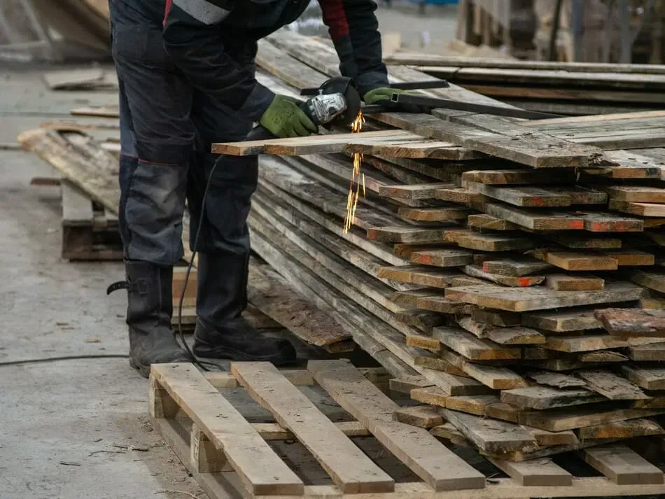 Un hombre está cortando un trozo de madera con una amoladora.