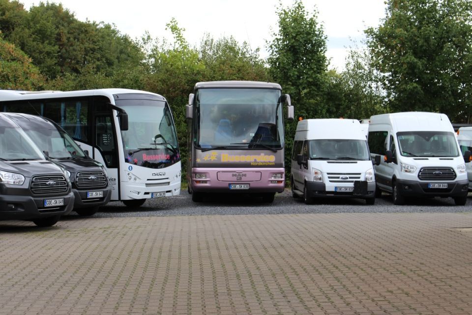 1 großer weißer Bus und ein altrosafarbener Bus