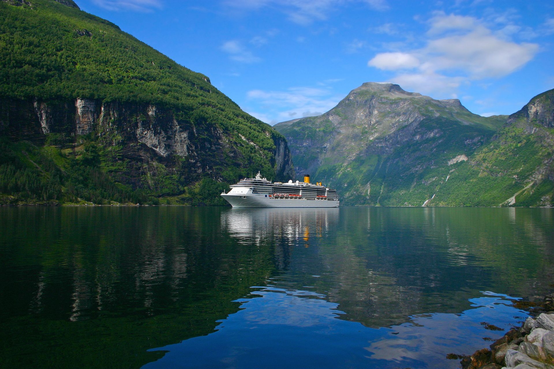 A cruise ship is floating on top of a lake surrounded by mountains.