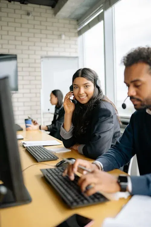 A man and a woman are sitting at a desk in front of a computer.