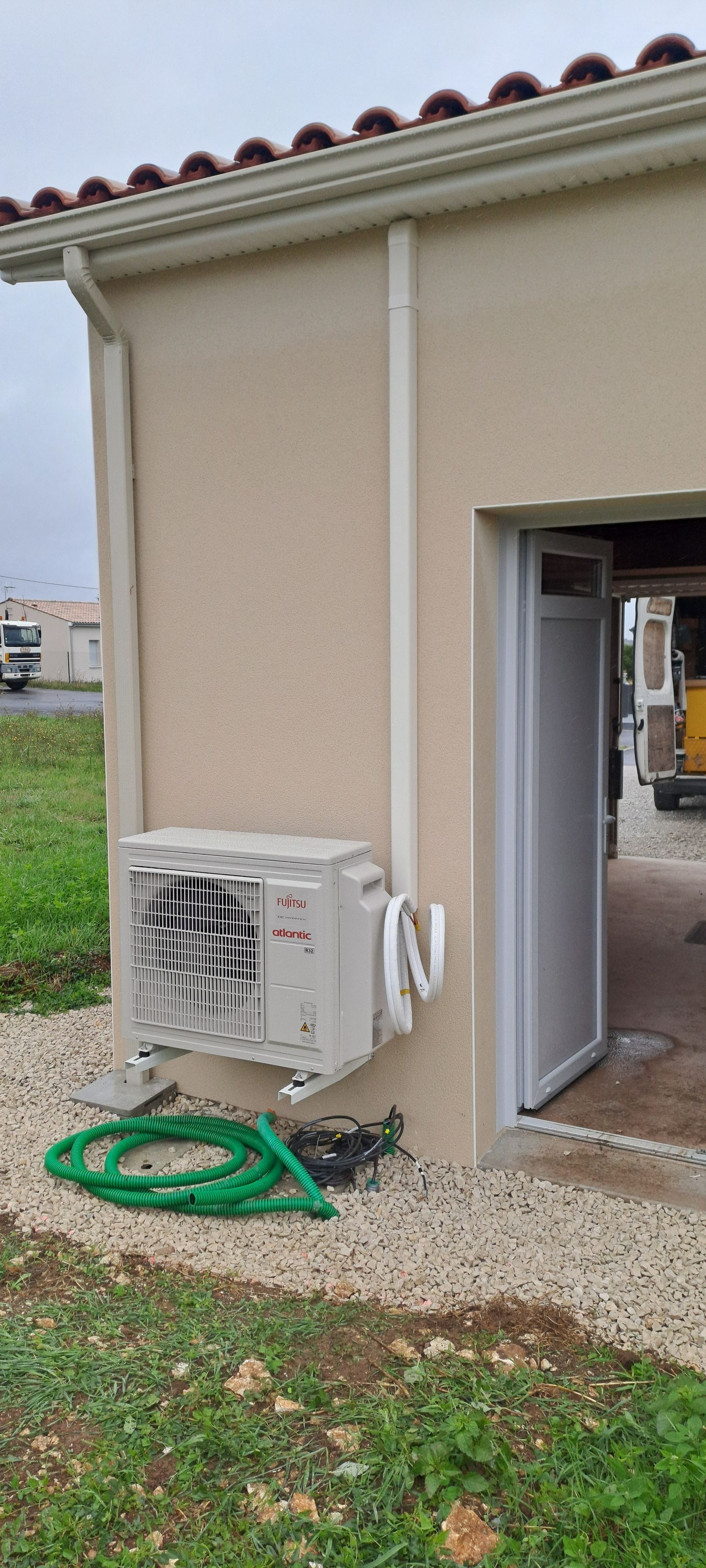 Un climatiseur extérieur est fixé sur le mur extérieur d'un bâtiment, près d'une porte ouverte.