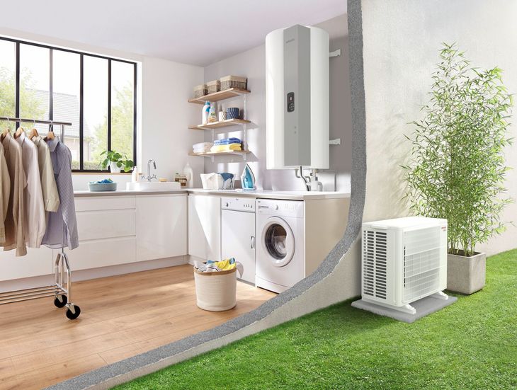 Buanderie avec chauffe-eau et pompe à chaleur extérieure. Vêtements sur un étendoir, machine à laver, plante de bambou
