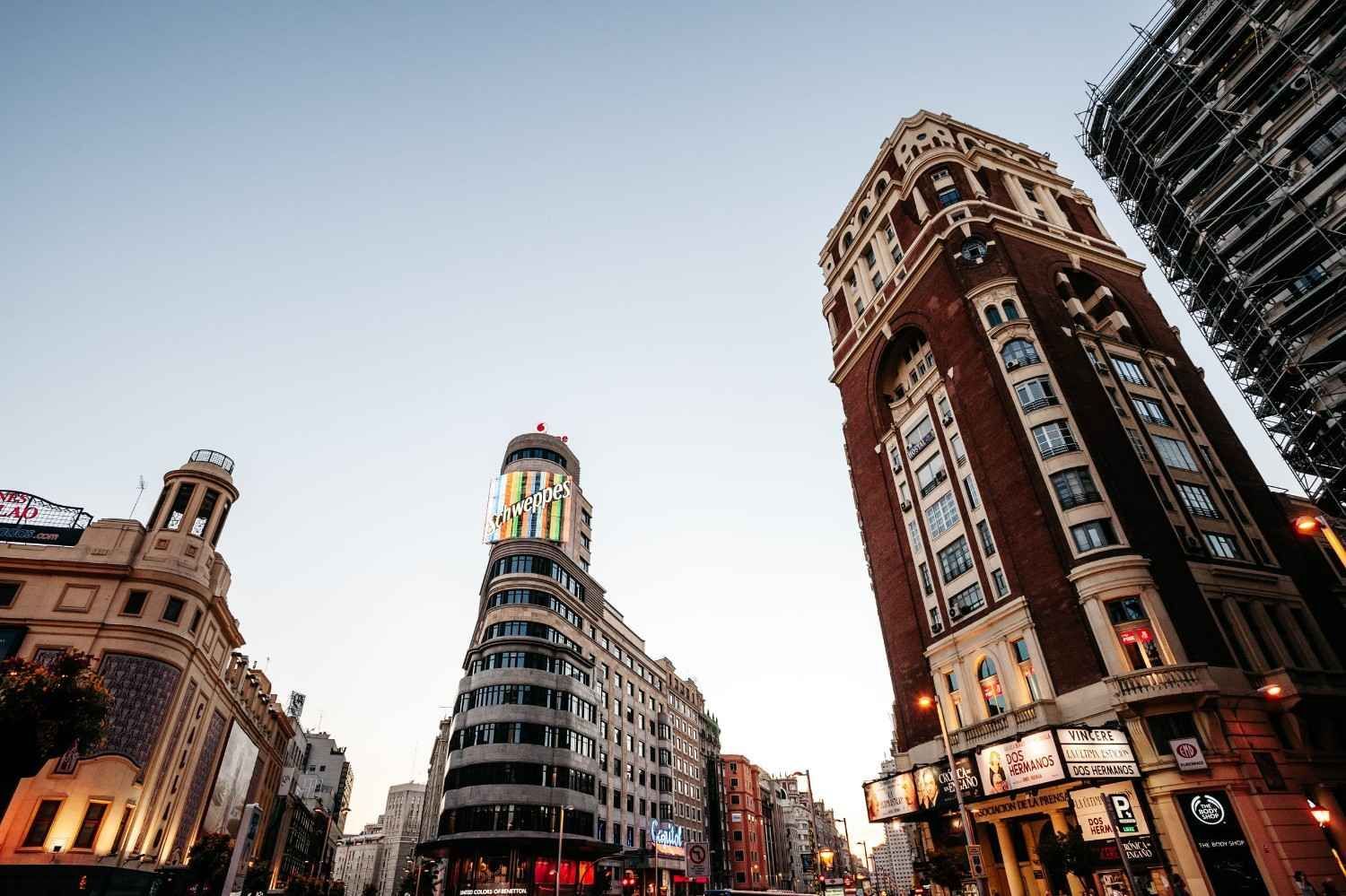 Calle de la ciudad con edificios históricos y una torre moderna en construcción al atardecer.