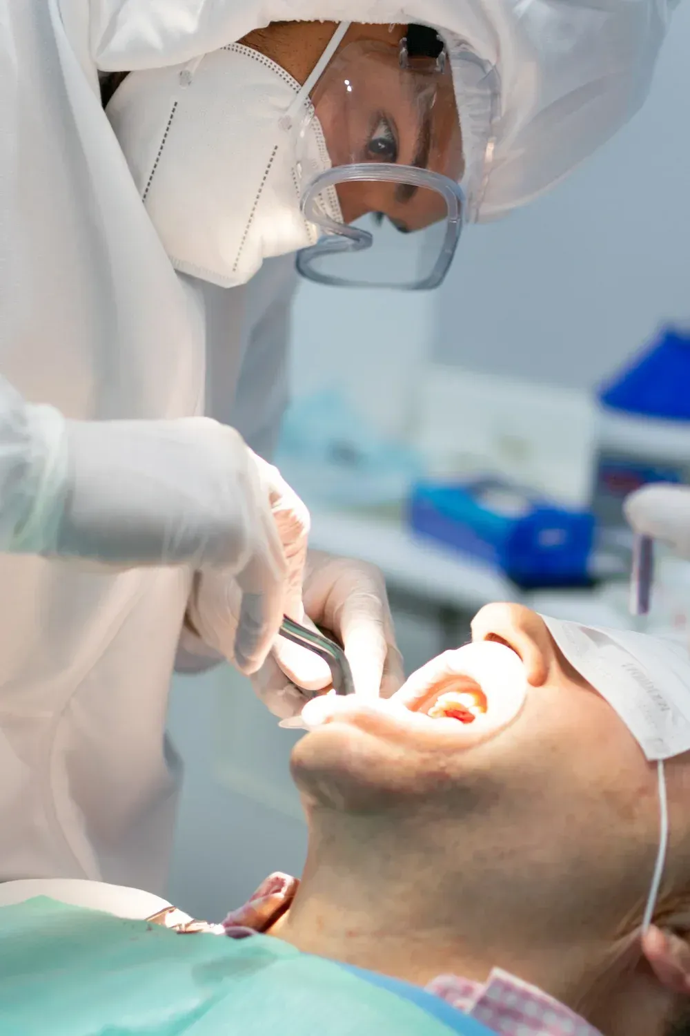Un dentista con equipo de protección realiza un procedimiento a un paciente en el sillón dental.
