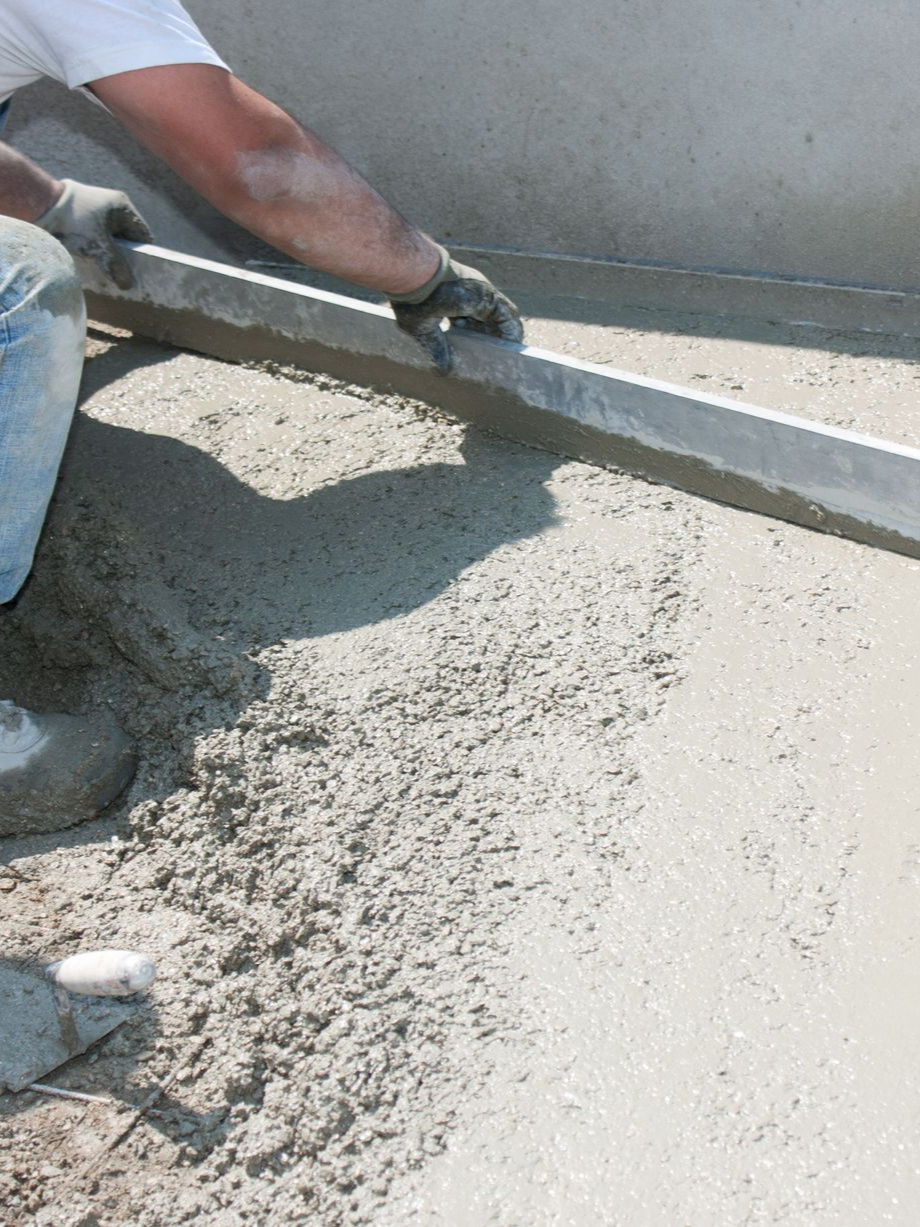 Personne utilisant un niveau pour lisser du béton humide.