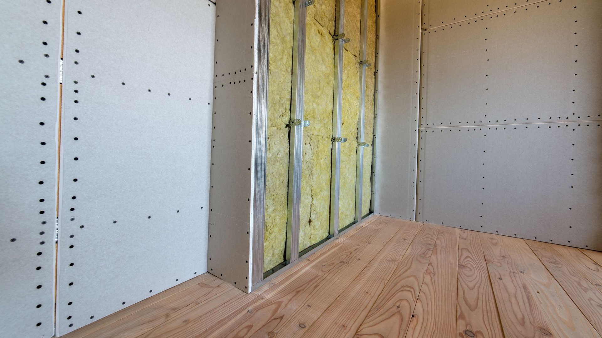 Intérieur d'une pièce en construction avec parquet, cloisons sèches et isolation.