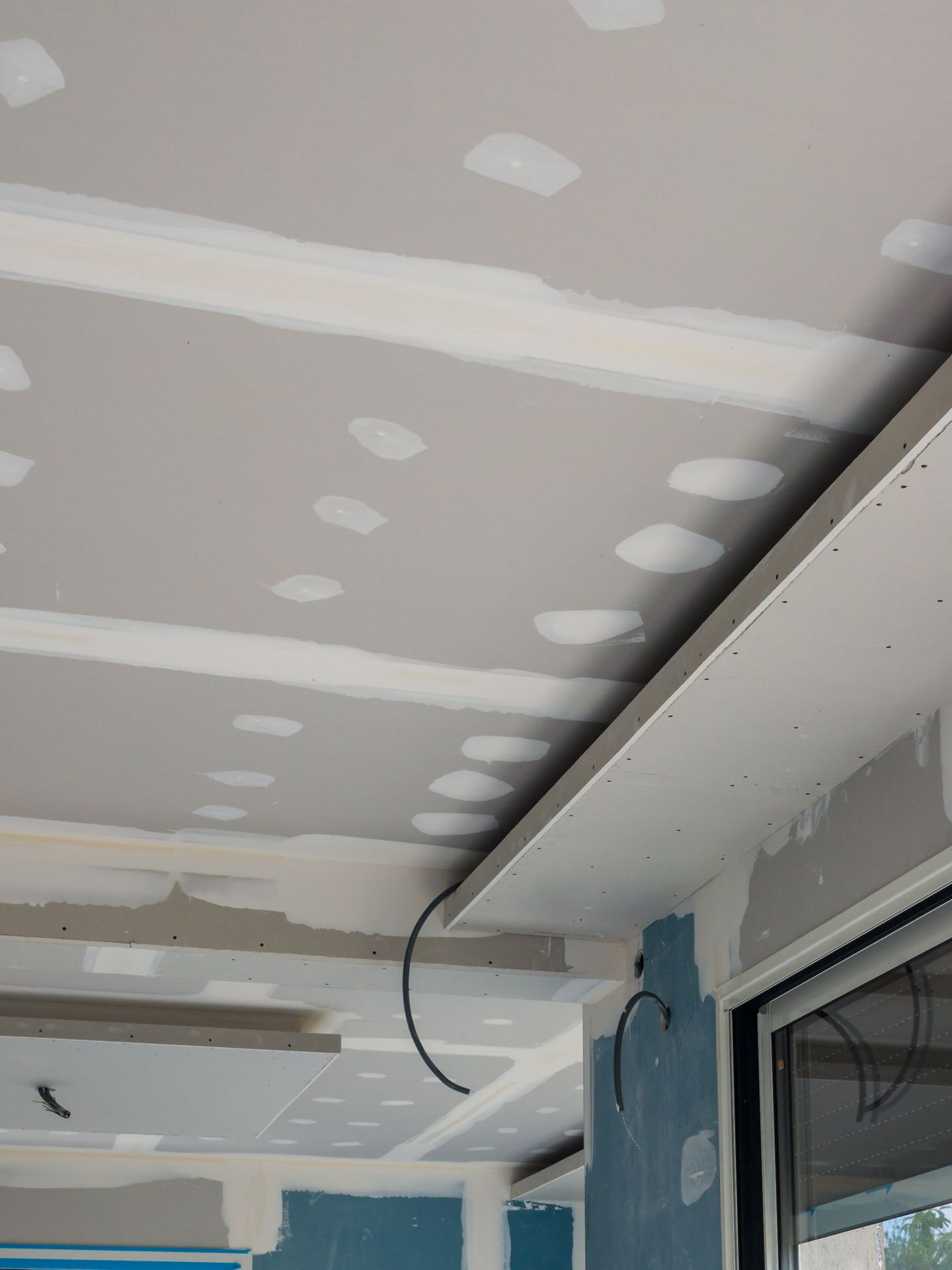 Pose d'un plafond en plaques de plâtre avec câblage électrique apparent.