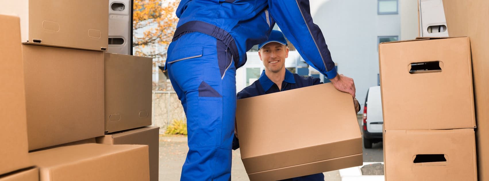 Un hombre con uniforme azul lleva una caja de cartón.