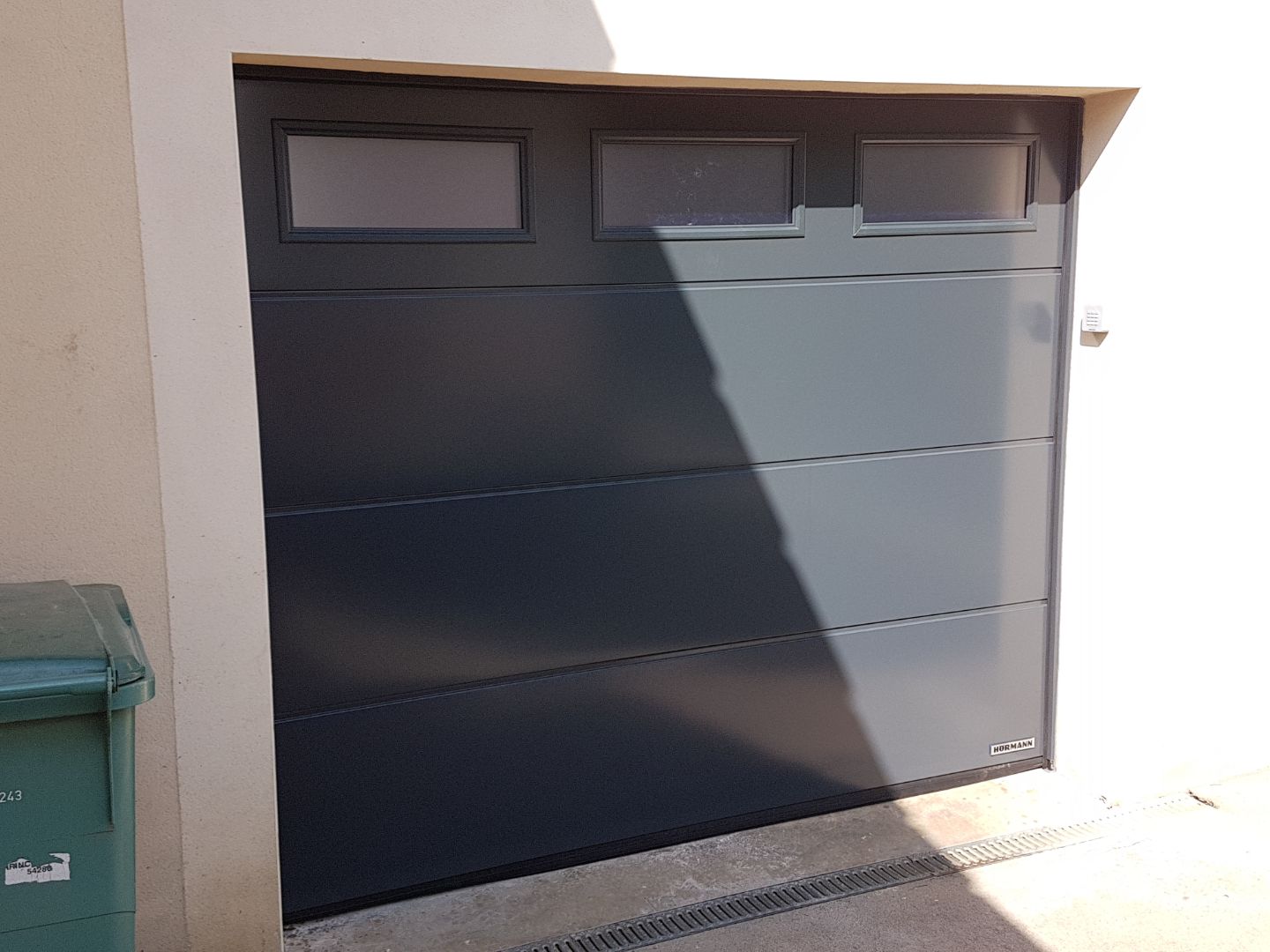 Porte de garage sectionnelle grise avec vitres