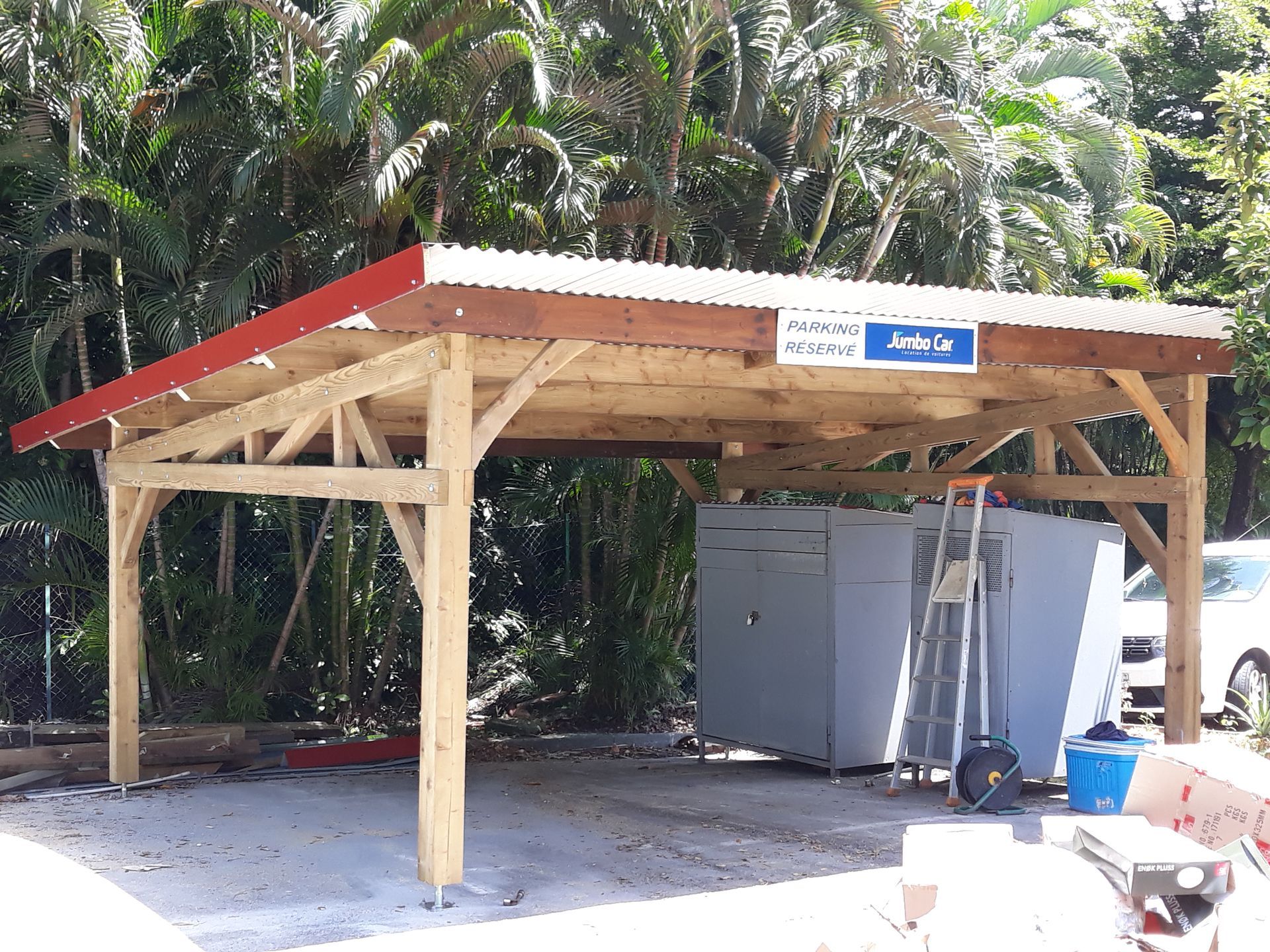 Pavillon en bois ouvert sur l’extérieur, avec un toit rouge et des armoires métalliques, dans un cadre tropical en plein air